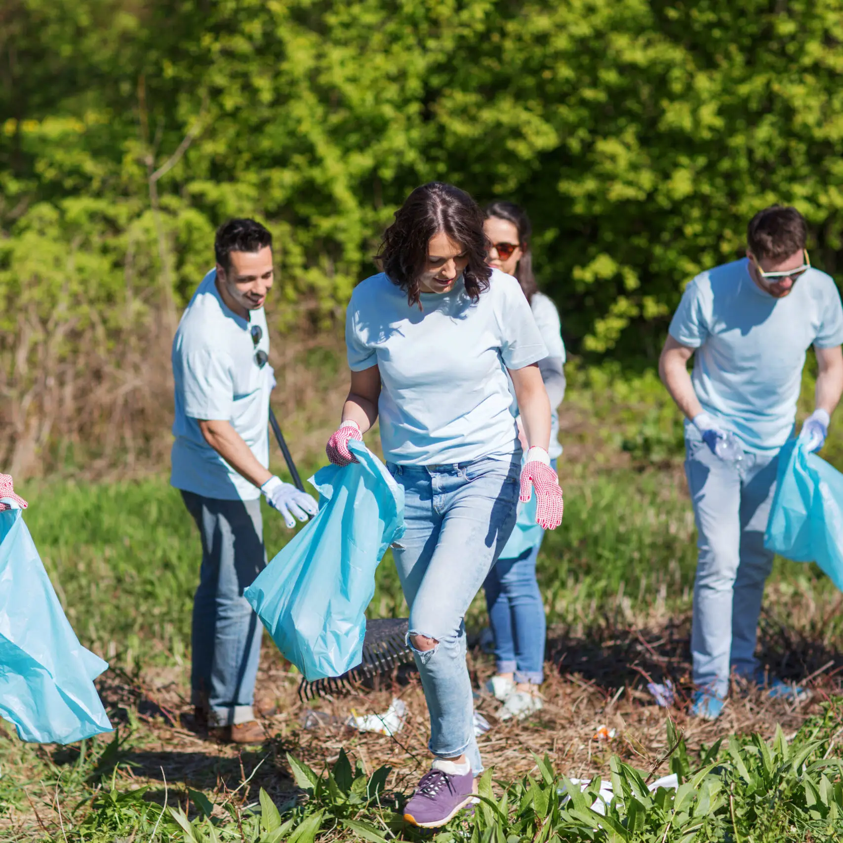 volunteering, charity, cleaning, people and ecology concept - group of happy volunteers with garbage bags cleaning area in park